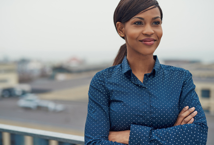 Photo of a confident black women in a button-up shirt.